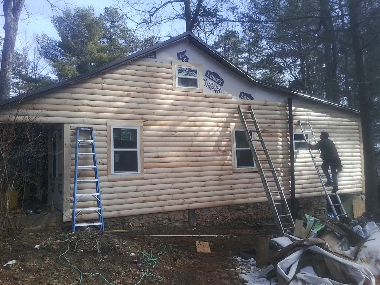 Ladders set against fresh log siding during an exterior remodel in Audubon