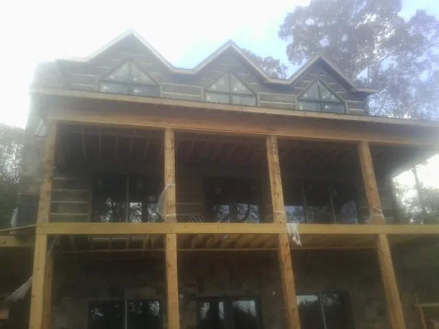 Dormers and porch framing on a large log home under construction — Roof Coating work by our crew in Audubon